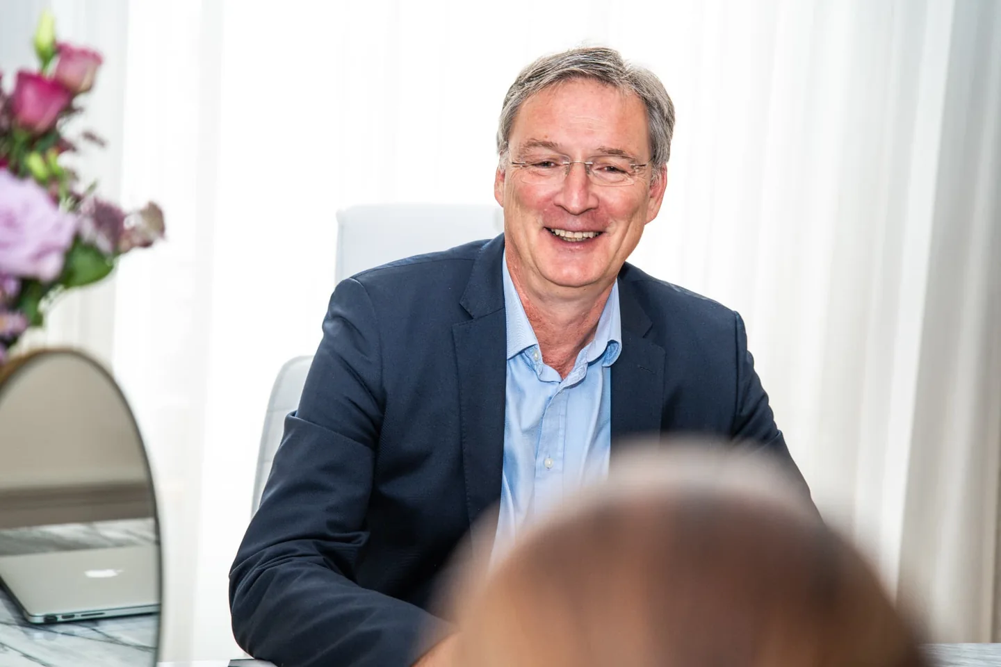 Dr. med. Michael W. Payne im Gespräch mit einer Person am Beratungstisch